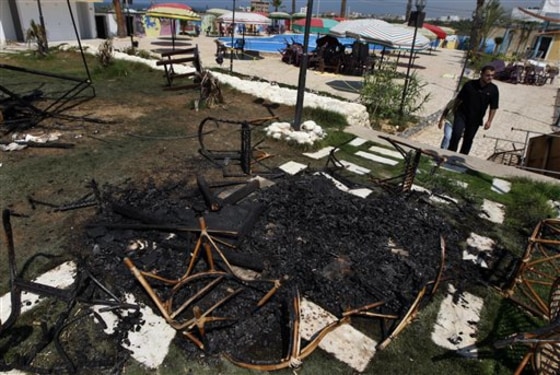 Palestinians check the damage at a water amusement park after it was set on fire in Gaza City, on Sunday. A Gaza amusement park accused of allowing men and women to sit together has been burned down. The park, which serves the territory's small elite, was shuttered by Hamas in August after men and women were seen mixing together.